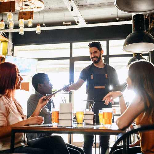 Waiter serving friends at restaurant table.