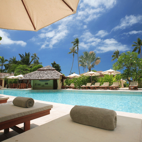 Tropical resort pool with lounge chairs and umbrellas.
