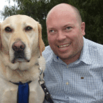Smiling man with guide dog outside