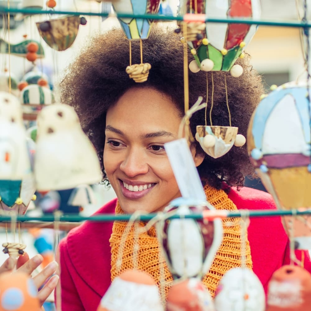Smiling person browsing colorful hanging ornaments.